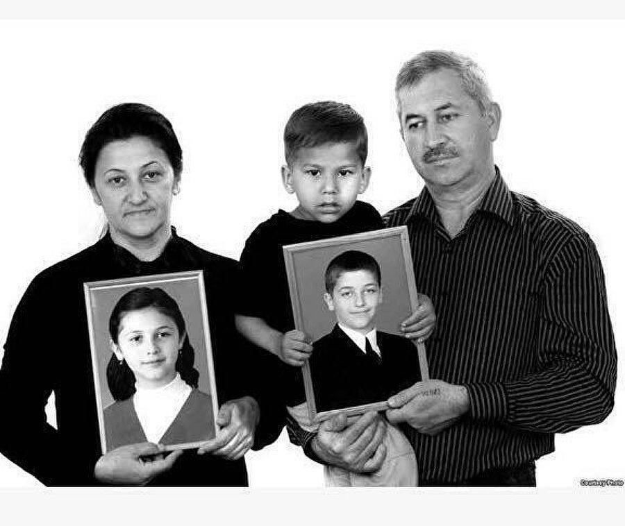 Эльвира Туаева вместе с мужем, маленьким Хетагом и фотографиями погибших детей